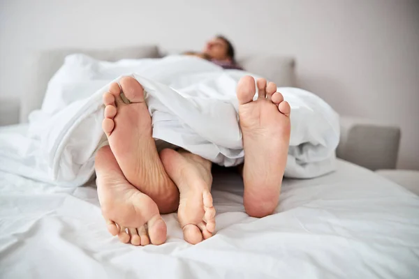 Jong paar in liefde rusten in bed met verweven benen — Stockfoto