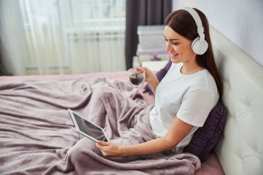 Bir fincan kahve ve tabletle rahatlayan bir kadın.