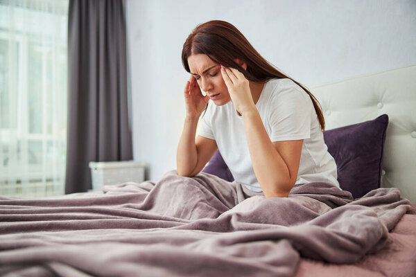 Woman having a headache and rubbing her temples