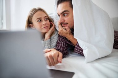 Yatak odasında dizüstü bilgisayar kullanan güzel bir çift.