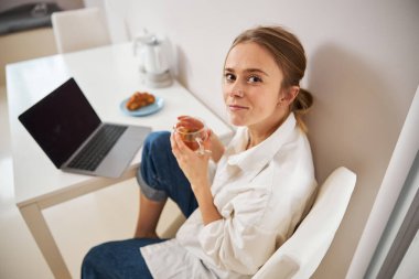 Evde çay içip defter kullanan çekici genç bir kadın.