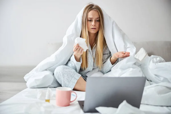 Sjuk ung kvinna som har online samråd med läkare hemma — Stockfoto