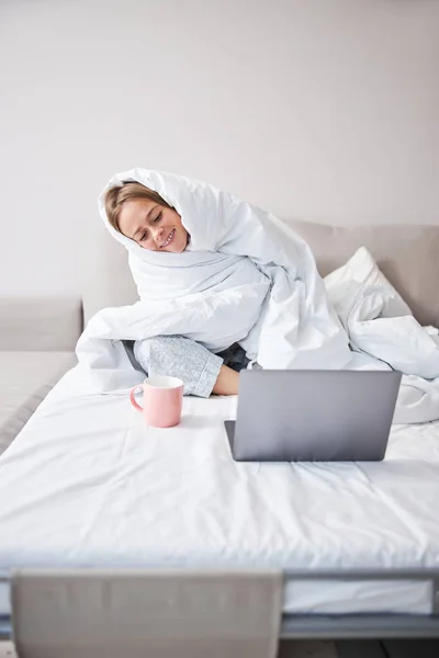 Joven alegre usando cuaderno en el dormitorio — Foto de Stock