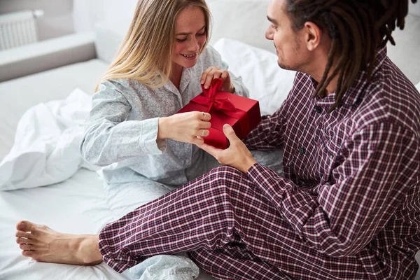 Sevgi dolu genç adam yatak odasında kız arkadaşına hediye veriyor.