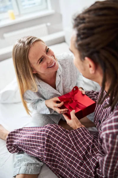 Fröhliche junge Frau nimmt Geschenkbox von Freund an — Stockfoto