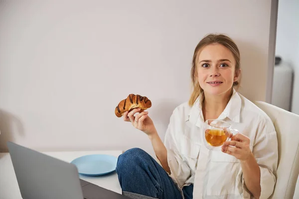 Чарівна молода жінка снідає і використовує блокнот вдома — стокове фото