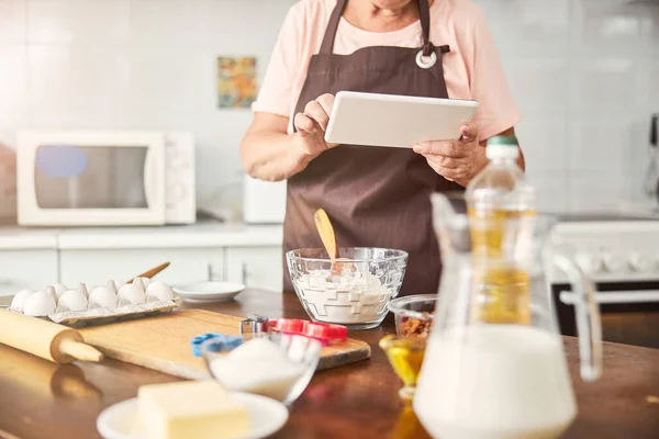 Уміла жінка-кухарка тримає планшет на кухні — стокове фото