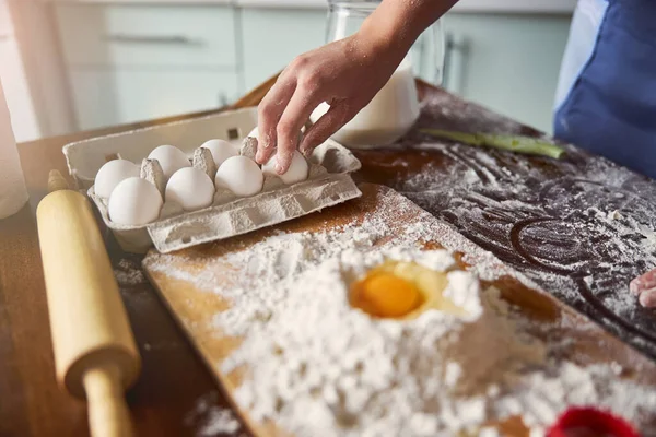 Уважний пекар збирає яйце, щоб додати до суміші тіста — стокове фото