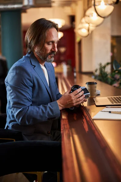 Serious traveler inspecting his photo-camera at a hotel — Zdjęcie stockowe