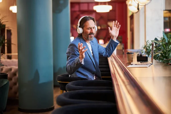 Delighted man enjoying listening to his playlist at hotel lounge — Zdjęcie stockowe