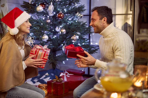 Солодка пара дарує подарункові коробки один одному у вітальні — стокове фото