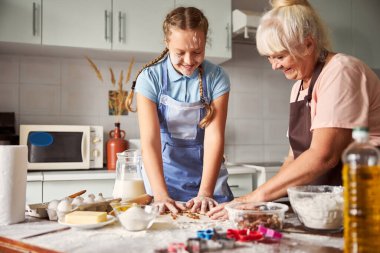Yaşlı kadın harika torunuyla yemek pişirirken kendini mutlu hissediyor.