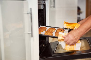 Kurabiyeleri fırından çıkarırken güvenlik egzersizi yapan dikkatli fırıncı.