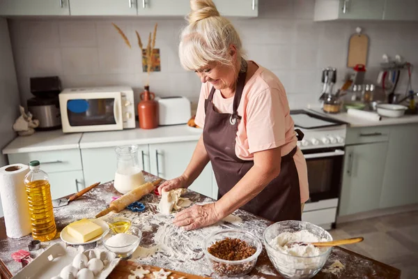 Любляча бабуся робить тісто для печива на кухні — стокове фото