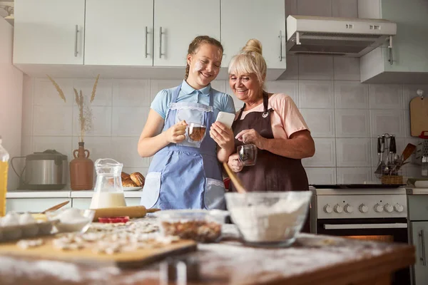 Весела дівчина-підліток і її бабуся насолоджуються чаєм разом — стокове фото