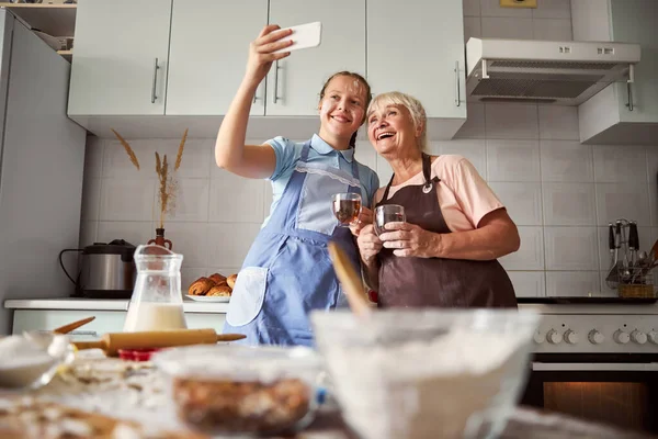 Feliz abuela y linda chica tomando selfie en la cocina — Foto de Stock