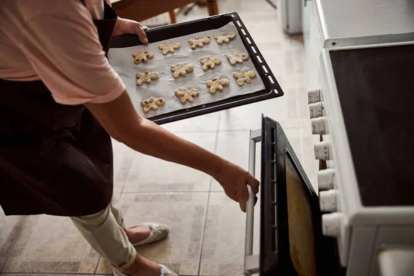 Дама готується вставити тісто у форму печива в гарячу піч — стокове фото