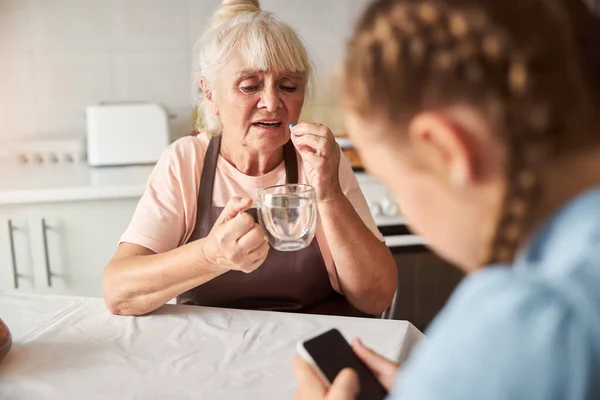 Zieke seniorendame die thuis medicatie neemt — Stockfoto
