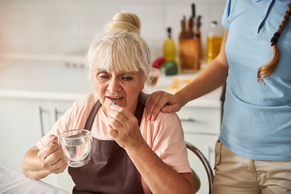 La abuela perturbada tomando su medicación con agua — Foto de Stock