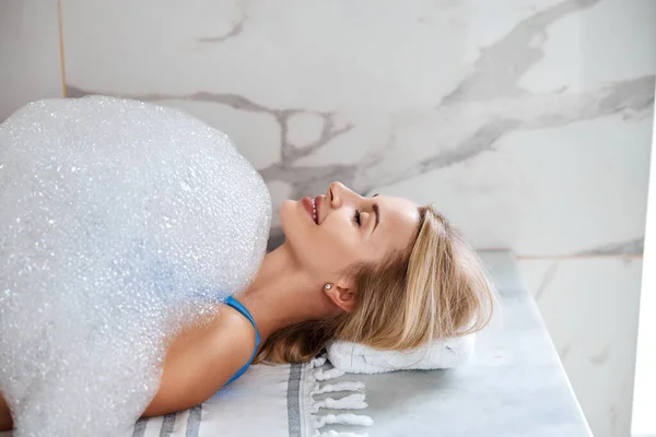 Jolie femme appréciant la procédure de spa avec mousse de savon dans le centre de beauté — Photo