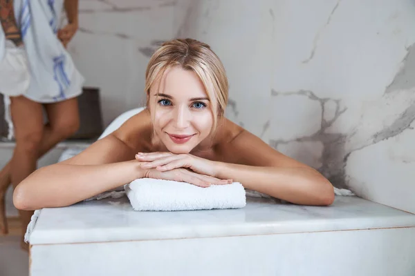 Glücklich lächelnde Frau liegt am Wochenende im Hamam auf dem Handtuch — Stockfoto