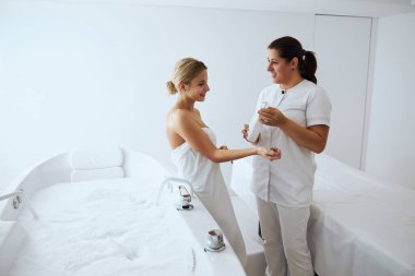 Doktor yeni vücut losyonunu gösterirken gülümseyen mutlu bayanlar sohbet ediyorlar.