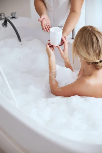 Heitere Dame liegt in gemütlicher Badewanne im Kosmetikzentrum — Stockfoto