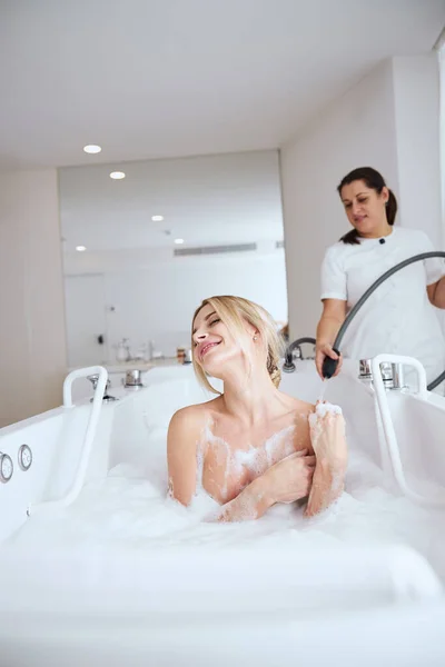 Mujer hermosa feliz con los ojos cerrados relajante en bañera de hidromasaje en el centro de spa — Foto de Stock