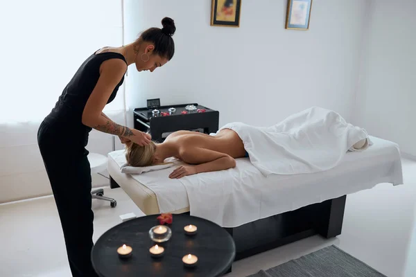 Affascinante massaggiatore donna che lavora con il paziente al tavolo giù in camera al chiuso — Foto Stock