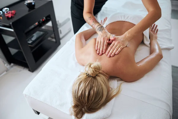 Расслабленная женщина получает массаж спины в роскошном спа-салоне с профессиональным массажистом — стоковое фото