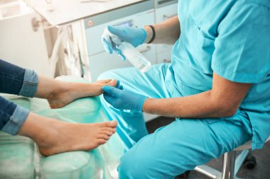 Uzman podolojist tırnaklarına antibakteriyel dezenfektan püskürtüyor.