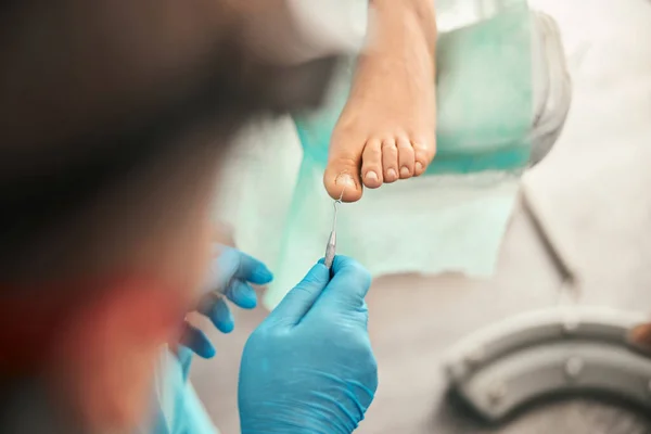 Attentive podologist doing medical pedicure for visitor — Stock Photo, Image