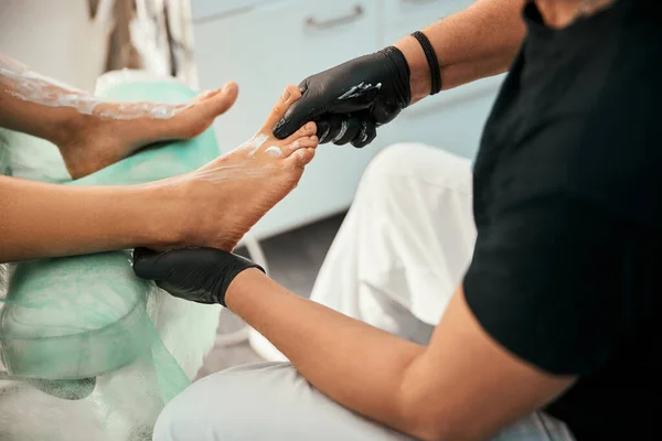 Competent podologist doing foot massage for patient — Stock Photo, Image