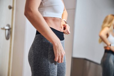 Zarif, güzel bir kadın. Aynanın karşısında durmuş, elinde derisi tutarken.