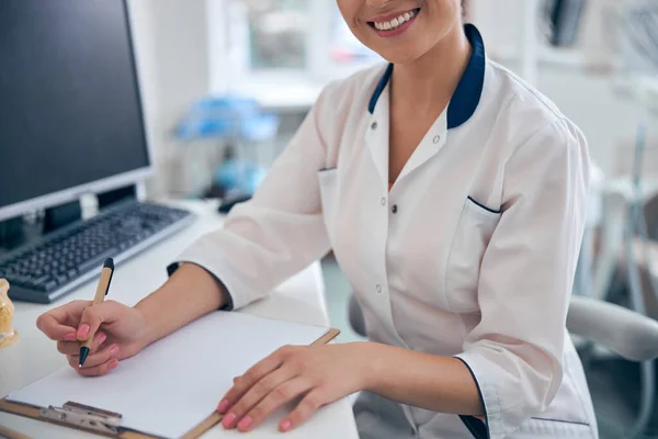 Dentiste souriante écrivant la prescription pour le patient — Photo