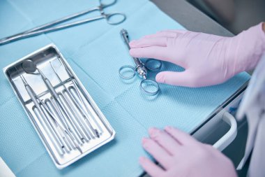 Ofiste çalışırken steril aletler kullanan diş hekimi