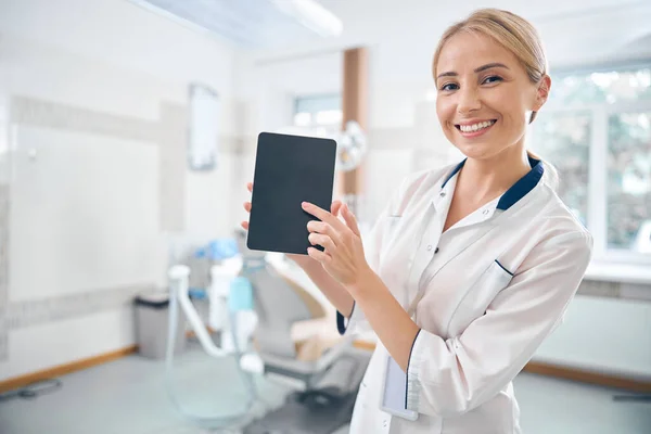 Dentiste féminine gaie en utilisant gadget moderne au bureau — Photo