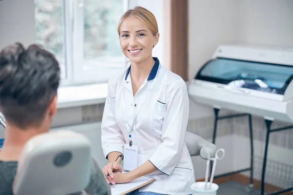 Ευτυχισμένη γυναίκα οδοντίατρος κατά την επίσκεψη των ανδρών στην κλινική — Φωτογραφία Αρχείου