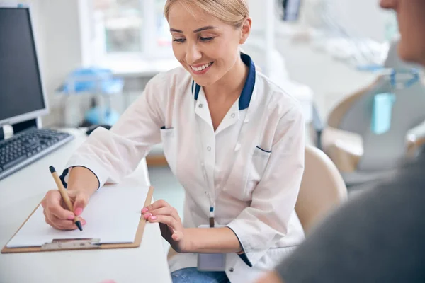 Dentiste féminine joyeuse travaillant avec la patiente au bureau — Photo