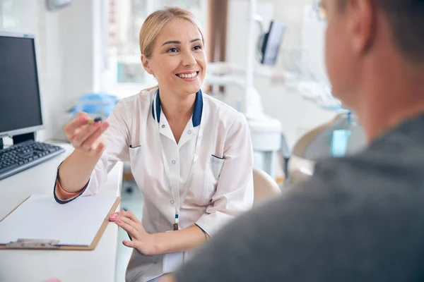 Dentista feliz feminino durante a visita com o homem — Fotografia de Stock