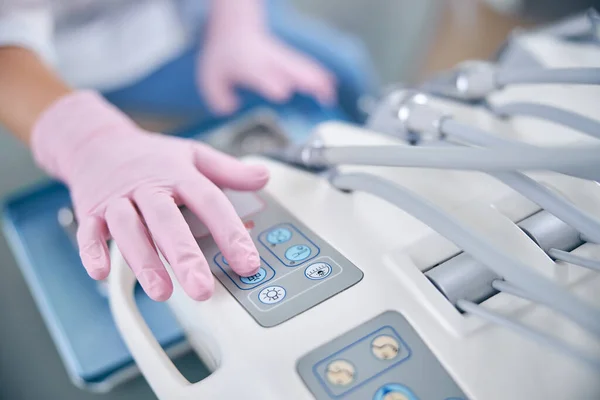 Vrouwelijke tandarts schakelt tandheelkundige machine in kantoor — Stockfoto