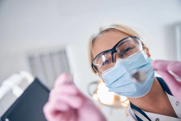 Vrolijke vrouwelijke tandarts met instrumenten in handen — Stockfoto