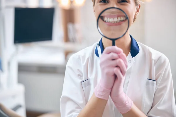 Dentiste féminine heureuse avec loupe dans les mains — Photo