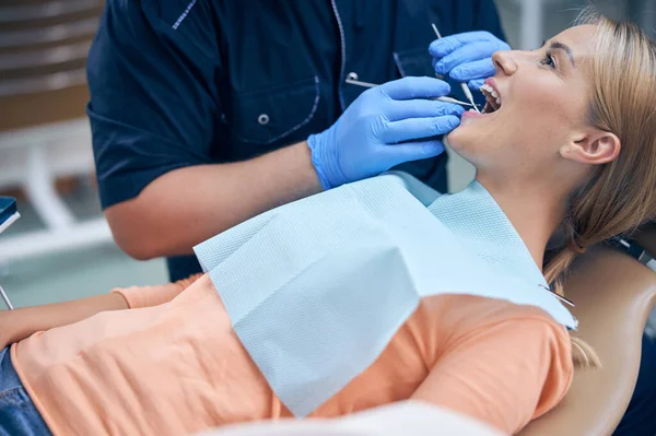 Vrolijke jonge vrouw wordt behandeld in tandheelkundige kliniek — Stockfoto
