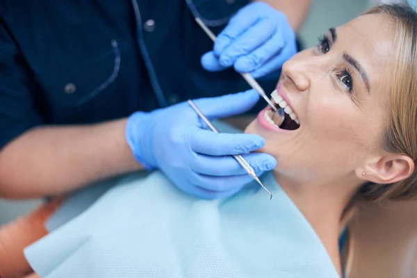 Jolly young woman being examined by dentist — Stock Photo, Image