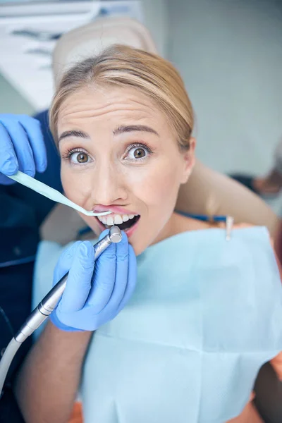 Młoda kobieta obawiająca się maszyny dentystycznej podczas leczenia — Zdjęcie stockowe