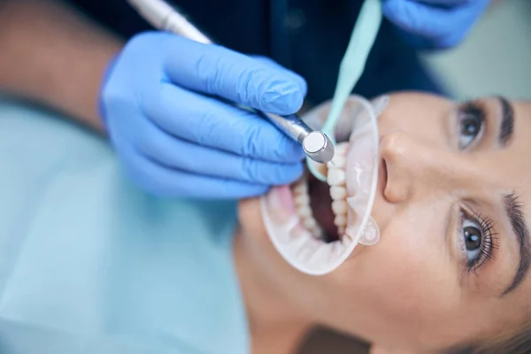 Dentista tratando joven hermosa hembra en la oficina — Foto de Stock