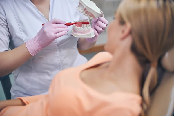 Dentystka wyjaśniająca prawidłowe czyszczenie zębów dla kobiety — Zdjęcie stockowe