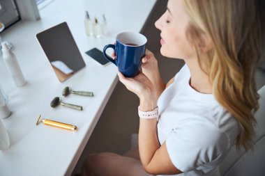 Mutlu beyaz kadın evde çay içiyor.