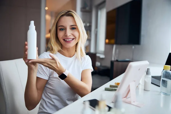 Attractive blonde Caucasian female advertising beauty cosmetic in room indoors — Stock Photo, Image